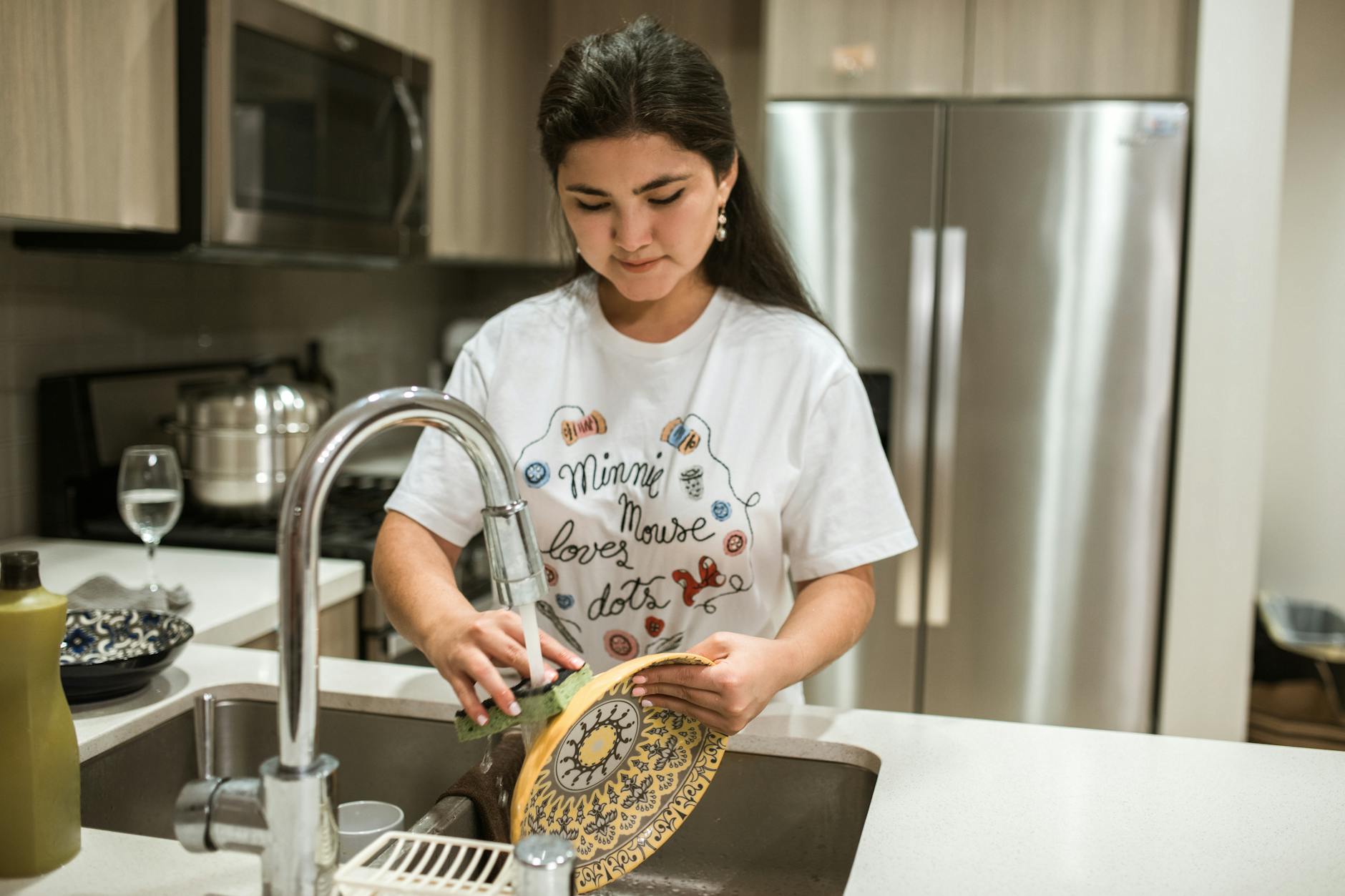 a woman in white shirt washing a fancy plate